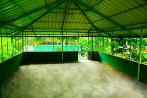 ein großes Gebäude mit einem Tennisplatz darin in der Unterkunft Shibi's Tea Garden Heritage in Vayittiri