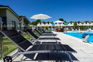 a row of lounge chairs next to a swimming pool at Domki wczasowe - Zielone Wzgórze - TOP COMFORT in Mielno