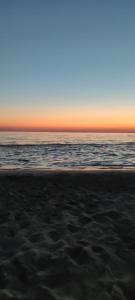 einen Strand bei Sonnenuntergang mit dem Ozean im Hintergrund in der Unterkunft Casa Conchiglia in Lido Conchiglia