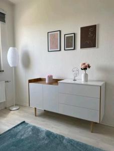 a living room with a white dresser and a lamp at Apartment Miesmuschelparadies in Lübeck