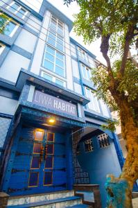 a blue and white building with a tree in front of it at Liwa Habitat in Bangalore