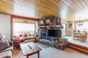 a living room with a stone fireplace with a tv at Downhill Beaverhead in Big Sky