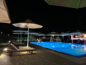 uma piscina com cadeiras e guarda-sóis à noite em Stomio Villague em Filiatrá
