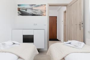 twee bedden in een witte kamer met een foto aan de muur bij Przestronny Apartament z Balkonem - Przy Porcie - Świnoujście by Renters in Świnoujście