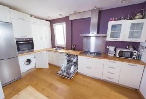 a kitchen with white cabinets and purple walls at Apartamento con terraza in Tarifa