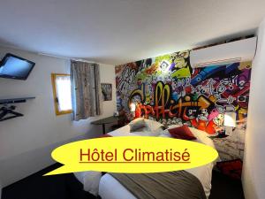 a bedroom with a bed with a wall covered in graffiti at Hôtel The Originals Access, Bourges Nord Saint-Doulchard in Bourges