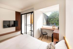 暖武里府Botanic Service Room at Impact Muangthongthani - SHA Certified的一间卧室，配有一张床、一张书桌和一扇窗户