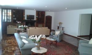 a living room with couches and a table with flowers at Pousada Matitaterê in Teresópolis
