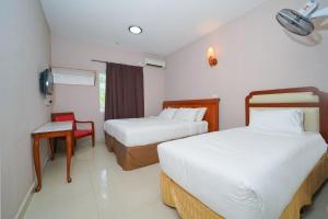 um quarto de hotel com duas camas e uma cadeira em Mila Motel 2 em Pantai Cenang