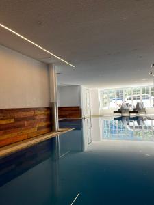 a swimming pool in a room with a table and chairs at Grichting Hotel & Serviced Apartments in Leukerbad