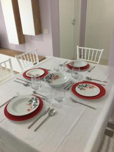 a table with red and white plates and wine glasses at Linda’s apartment in Vlorë