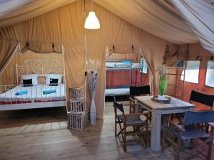 namiot ze stołem, krzesłami i łóżkiem w obiekcie Tente Lodge Safari w mieście Saint-Martin-des-Besaces