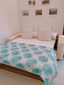 Una cama con una manta azul y blanca. en Villetta con Piscina e Campo da Tennis condominiale en Villasimius