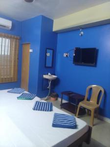 a blue room with a bed and a chair and a sink at New City Tower Residency in Tiruchchendūr