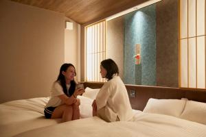 twee vrouwen op een bed in een hotelkamer bij 古今 天下茶屋 with a private parking lot and a half open-air bath and direct to KIX in Osaka