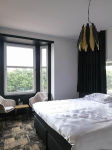 a bedroom with a large bed and two windows at Bed & Breakfast Maison Noire Westende-bad incl parking & ontbijt in Middelkerke