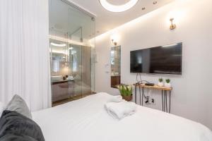 a bedroom with a white bed and a tv at Colors Suites in Netanya in Netanya
