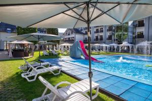 a pool with umbrellas and chairs in it at Hotel Verde Montana Wellness & Spa in Kudowa-Zdrój
