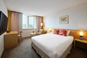 a hotel room with a large bed and a television at Jeju Central City Hotel in Jeju