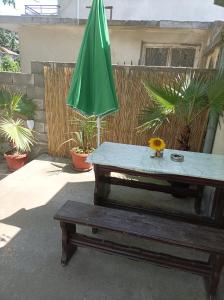 a green umbrella and a table and a bench at Вила Радеви in Obzor +25 photos