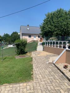 a house with a fence and a brick walkway at Hibiskus Appartementhaus in Cserszegtomaj