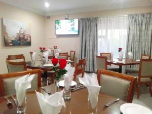 a dining room with a table with red roses on it at Benoni N12 Hotel in Benoni