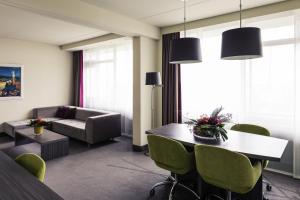 a living room with a table and chairs and a couch at Mercure Hotel Groningen Martiniplaza in Groningen