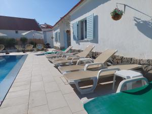 a row of lounge chairs next to a swimming pool at Villa Mariana Piscina Privada in Porto Covo