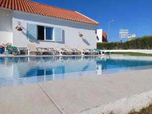 a swimming pool with chairs and a house at Villa Mariana Piscina Privada in Porto Covo