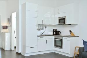 cocina blanca con armarios blancos y microondas en Ferienwohnung Kala, en Juliusruh