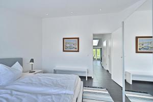 a white bedroom with a bed and a hallway at Ferienwohnung Kala in Juliusruh