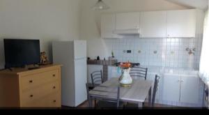 a kitchen with a table with chairs and a refrigerator at L'ulivo e lo scoiattolo in Marina Palmense +11 photos