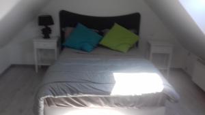 een bed met groene en blauwe kussens in een kamer bij Beau studio au calme proche de la cathédrale in Autun
