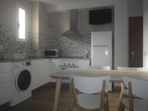 a kitchen with a table and a white refrigerator at Cal toà in Coll de Nargó