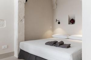 a bedroom with a white bed with towels on it at Petragrigia Vacation Suite in Ostuni