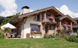 ムジェーヴにあるChambres d'Hôtes Chalet Eternel Mont-Blancのポーチ付きの家、花の咲くバルコニー付きの家