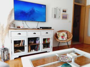 a living room with a tv on top of a white cabinet at Aska Apartment in Bar