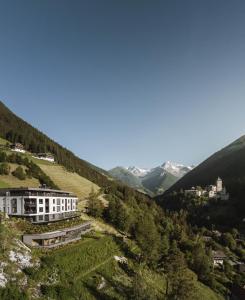 un bâtiment sur une colline avec des montagnes en arrière-plan dans l'établissement AhriaPura, à Sand in Taufers