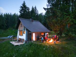 a group of people sitting around a fire in front of a house at Gemütliche Berghütte in den Alpen in Sonnenalpe Nassfeld