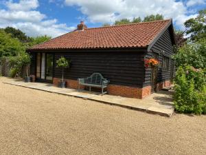 une petite maison avec un banc devant elle dans l'établissement Brundish Suffolk Barn 2 Bed Idyllic 6 acres, à Wilby