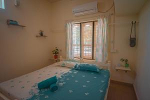 een slaapkamer met een bed met blauwe lakens en een raam bij Baba Luru's in Varkala