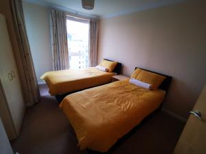 two beds in a hotel room with a window at Town Centre Penthouse in Basingstoke