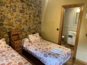 1 Schlafzimmer mit 2 Betten und einer Steinmauer in der Unterkunft Casa Rural El Medico in Serradilla del Arroyo + 13 Fotos