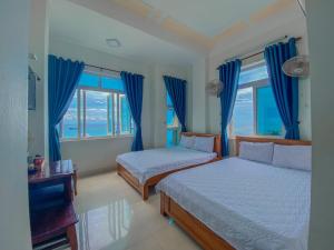 1 Schlafzimmer mit 2 Betten und blauen Vorhängen in der Unterkunft Binh Yen Hotel in Ly Son