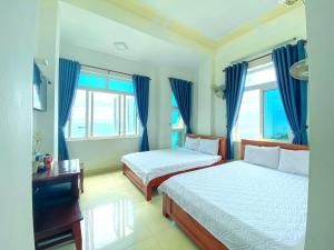 a bedroom with two beds and blue drapes at Binh Yen Hotel in Ly Son