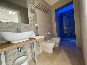 een badkamer met een wastafel, een toilet en een spiegel bij Domus Bianca Lancia in Manfredonia