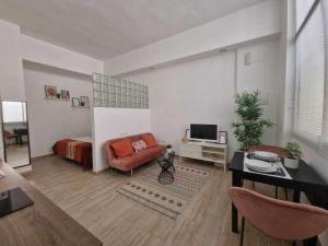 a living room with a couch and a bed and a television at Encantador estudio en Alameda de Hércules in Seville