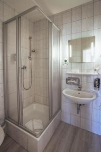 ein Bad mit einer Dusche und einem Waschbecken in der Unterkunft REGIOHOTEL Wolmirstedter Hof Wolmirstedt in Wolmirstedt
