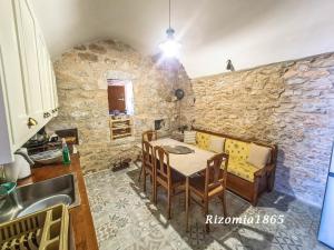 a kitchen with a table and a stone wall at Rizomia 1865 in Gerolimenas