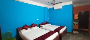 1 dormitorio con 2 camas y paredes azules en Selvasi Beach Cottage, en Auroville